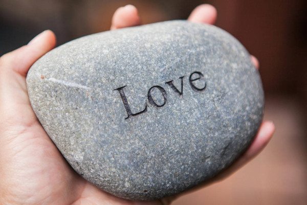 Hands holding pebble stones with the word love